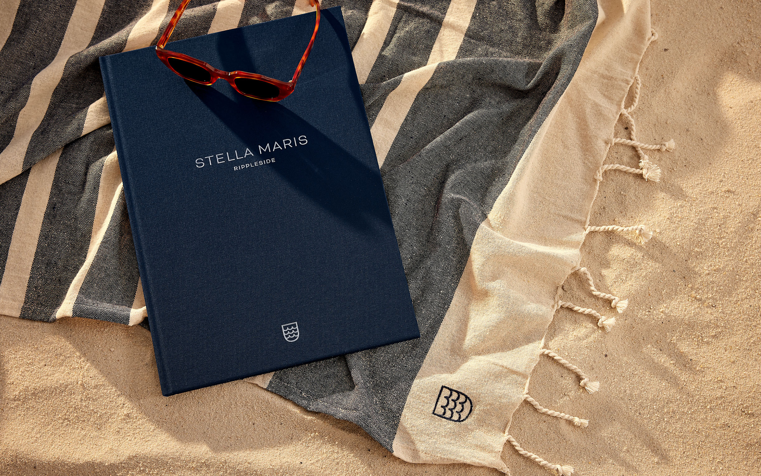 Brochure laying on branded towel in sand