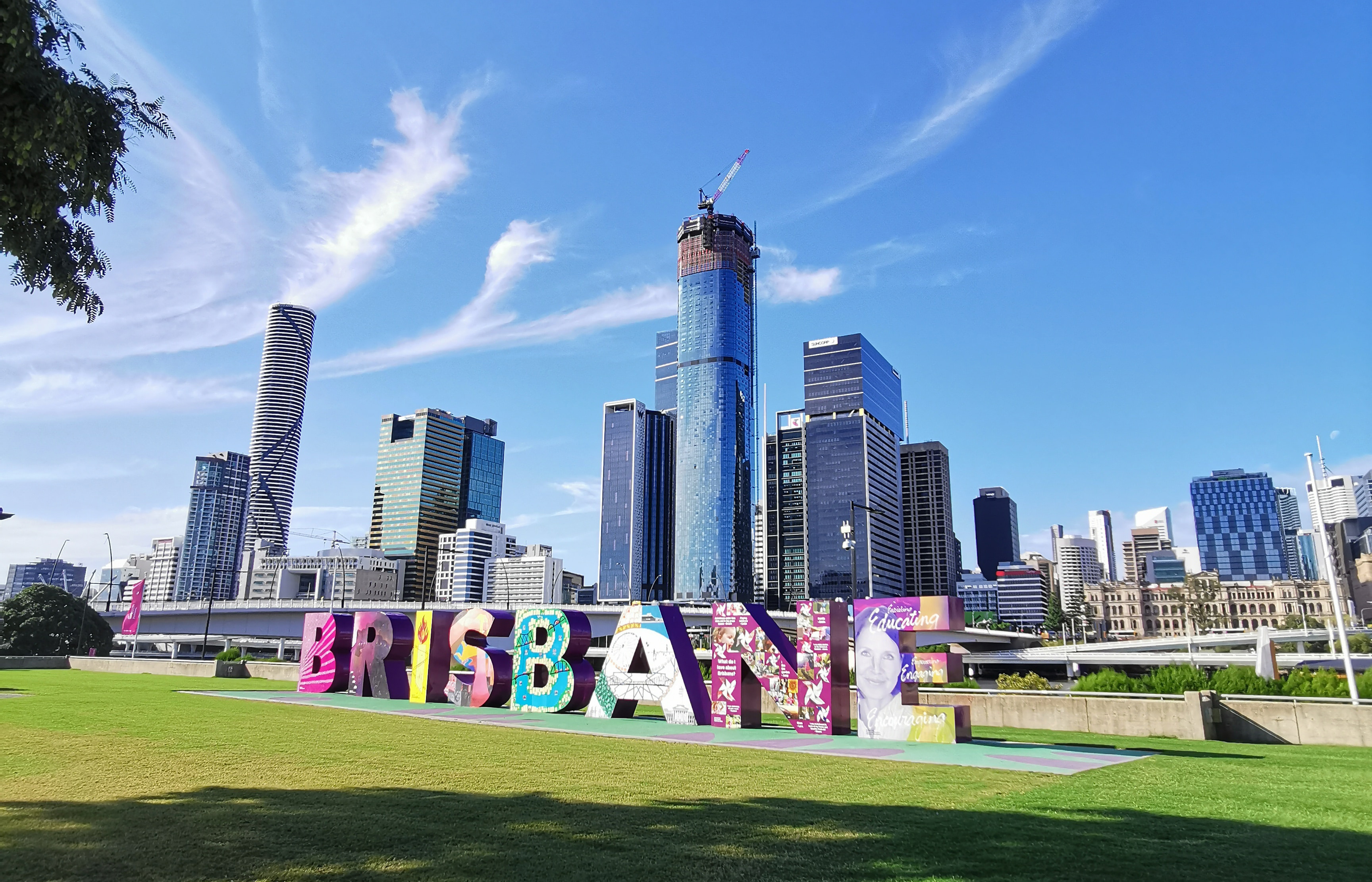 3D letters spelling Brisbane on lawn in front of Brisbane river and skyline