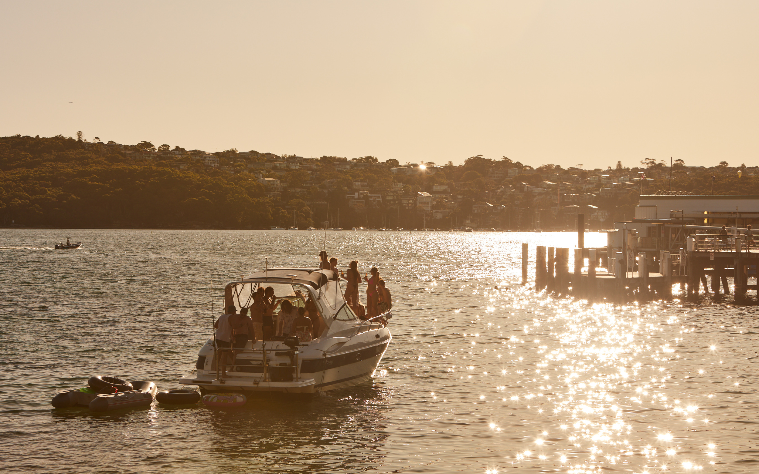 Image of friends on a boat in late afternoon just off a pier in Manly